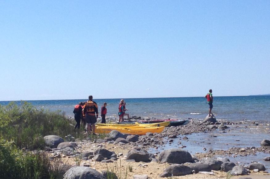 Group of people in lifejackets preparing to launch kayaks into Lake Michigan